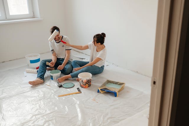 two people smiling while painting their apartment